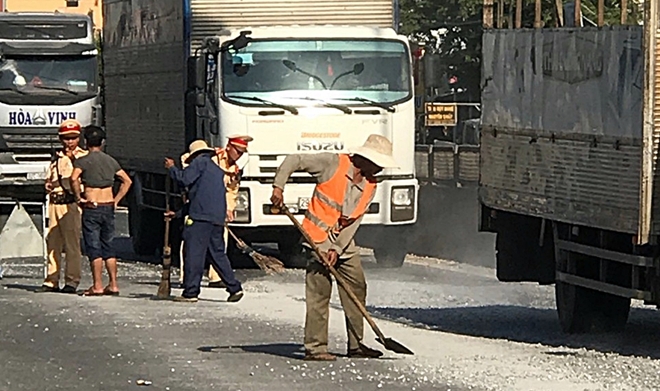 Lực lượng Cảnh sát giao thông Quảng Nam và người dân "đội nắng" thu gom đá dăm rơi vãi.