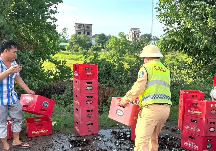 Tổ CSGT đường bộ số 5 cùng người dân giúp đỡ lái xe thu dọn số bia chai bị vỡ trên đường.