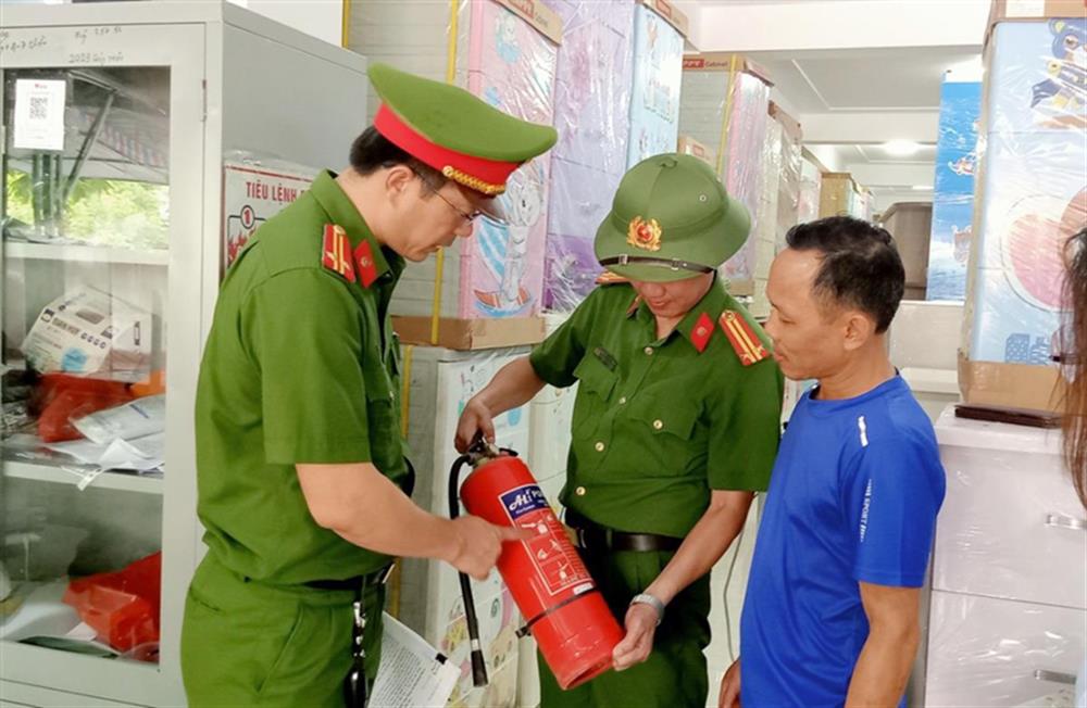 Cán bộ Công an hướng dẫn người dân sử dụng bình chữa cháy.