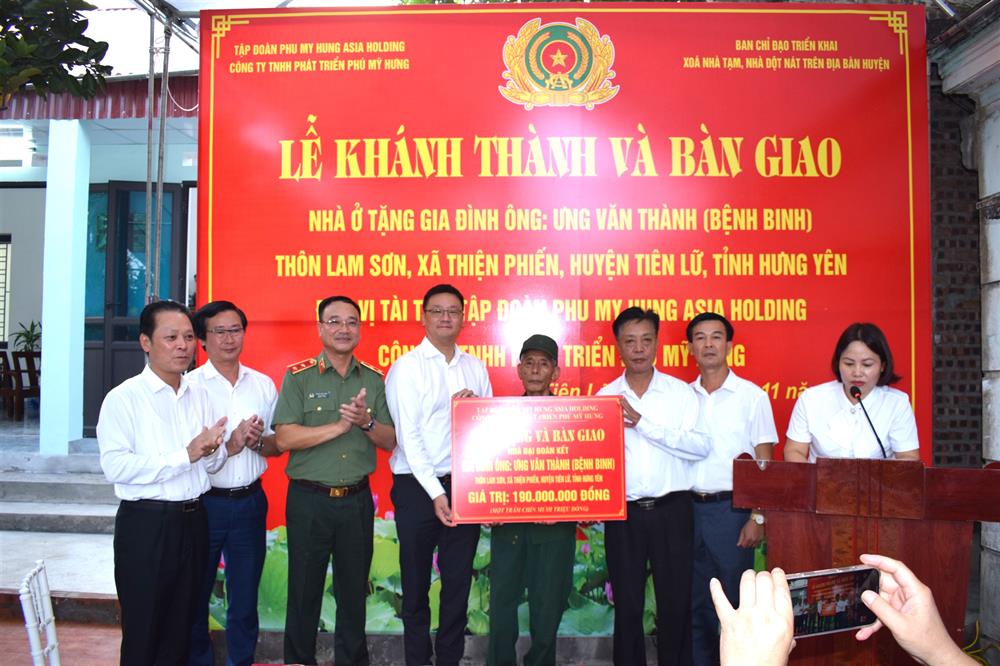 Trung tướng Phạm Thế Tùng, Thứ trưởng Bộ Công an cùng nhà tài trợ và các đại biểu trao tiền hỗ trợ xây nhà tặng gia đình ông Ưng Văn Thành.