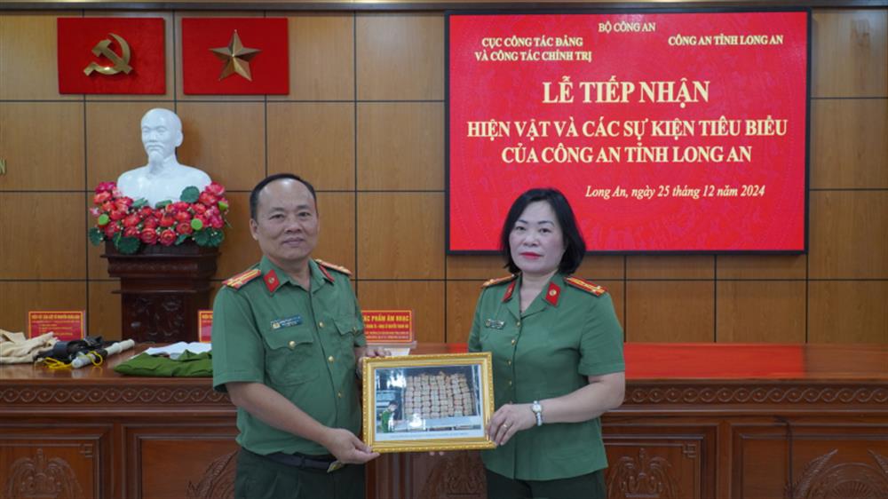 Đại diện Cục Công tác đảng và công tác chính trị, Bộ Công an tiếp nhận hiện vật của Công an tỉnh Long An.
